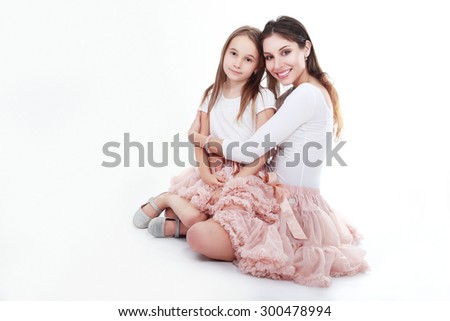 mother and daughter in same outfits posing on studio hugging