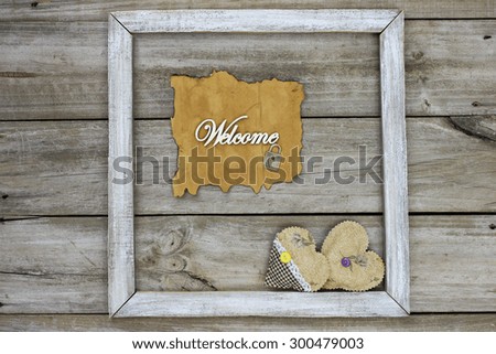 Antique parchment paper welcome sign on rustic wood background with country fabric hearts border
