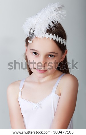 Portrait of cute little girl in luxurious dress and headbundle with feathers. Fashion photo