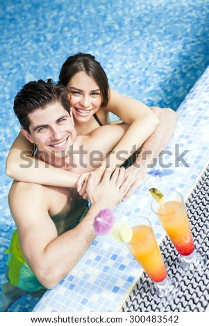 Couple drinking a cocktail by the swimming pool and relaxing