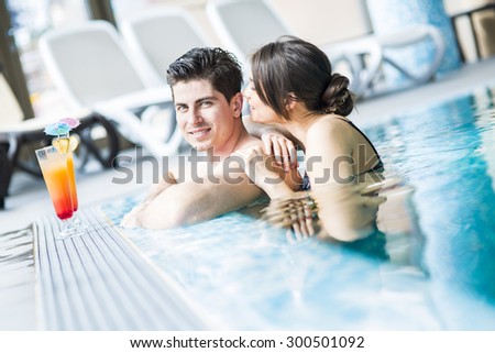 Couple drinking a cocktail by the swimming pool and relaxing