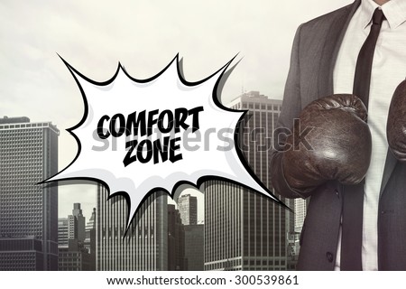 Comfort zone text with businessman wearing boxing gloves on cityscape background