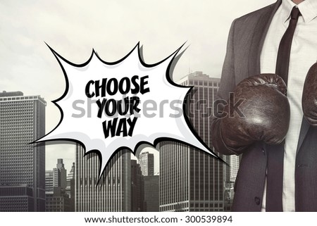 Choose your way text with businessman wearing boxing gloves on cityscape background