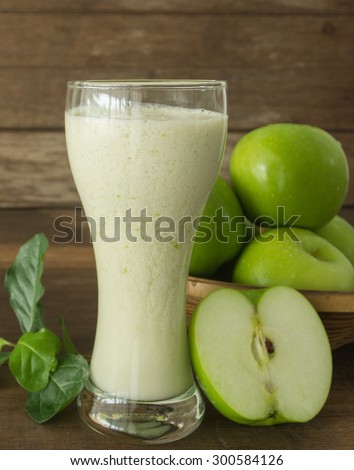 green apple juice in glass on wooden background
