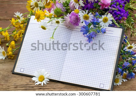 Bouquet of wildflowers and notebook with empty space for text. Good for holiday greetings
