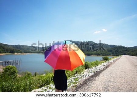 Woman alone color pattern of an umbrella with the sky as background.