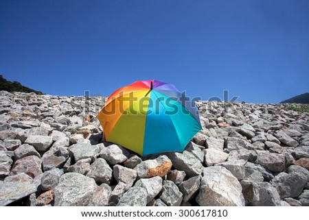 Color pattern of an umbrella with the sky and stone as background.