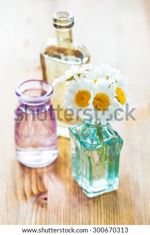 Bouquet of chamomiles in a small glass vases on wooden background