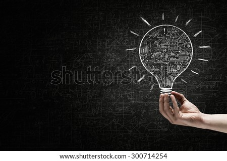Human hand on dark background holding light bulb 