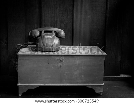 Vintage telephone on old table black and white still life photo.