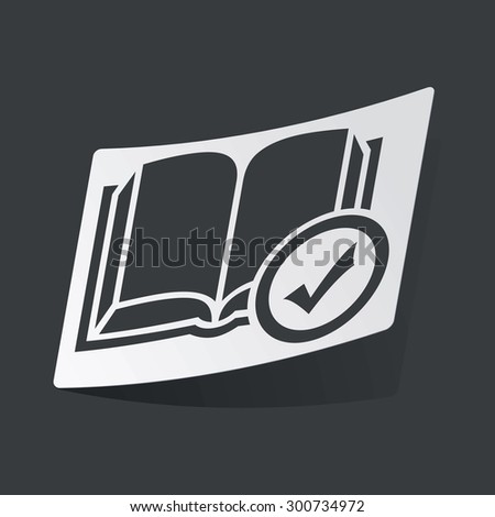 White sticker with black image of book with tick mark, on black background