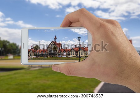 Tourist hand holding smart phone, taking photo of Auckland New Zealand, Whakarewarewa Springs