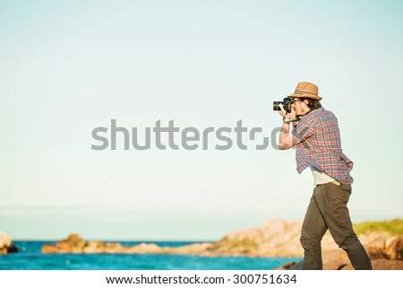 Young photographer taking photos at the beach of the beautiful seascape in sunet light