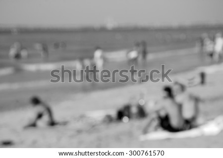 Blurred beach photo with bokeh. People relaxing on beach. Vacation background (Trouville-sur-Mer, Normandy, France) Retro aged photo. Black and white.