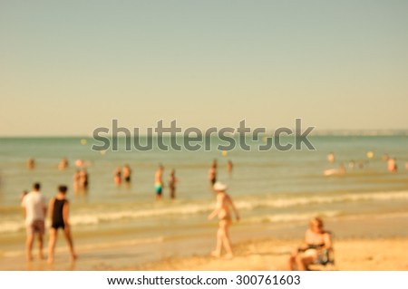 Blurred beach photo with bokeh. People relaxing on beach. Vacation background (Trouville-sur-Mer, Normandy, France) Retro aged photo. 