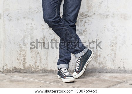 Regular Fit Straight Leg Jeans and Retro Canvas High Top Sneakers on Plaster wall background, selective focus (detailed close-up shot) Royalty-Free Stock Photo #300769463