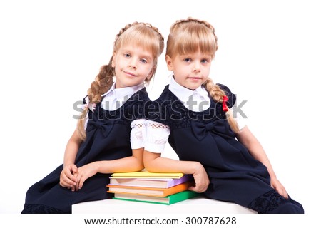 Curious cute little girl on white background sitting at desk with books in their hands in elegant dresses and smiling. The picture with depth of field