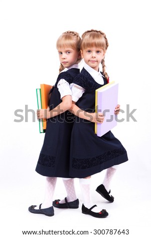 Curious cute little girl on a white background standing with books in hands in elegant dresses and smiling. The picture with depth of field