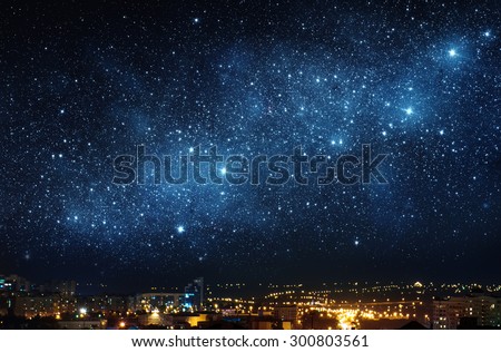 City landscape at nigh with sky filled with stars. Elements of this image furnished by NASA. Royalty-Free Stock Photo #300803561