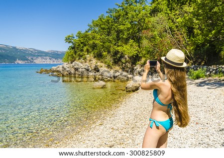 Young attractive girl taking photo on tropical beach