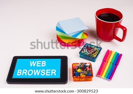 Business Term / Business Phrase on Tablet PC - Colorful Rainbow Colors, Cup, Notepad, Pens, Paper Clips, White surface - White Word(s) on a cyan background - WEB BROWSER