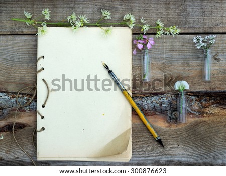 old sheet of paper located on a wooden surface, surrounded by wildflowers and old pen