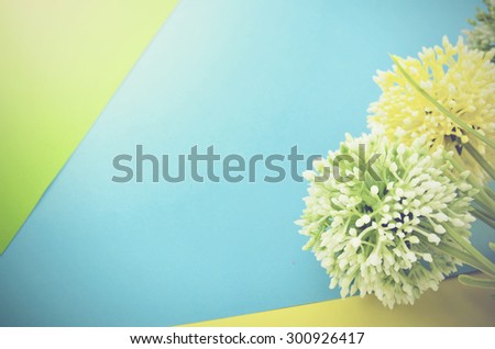 retro and vantage look green, white and yellow artificial flower image with light on top left. green, blue and yellow background