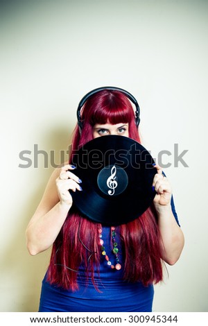 Young pretty woman looking with headphones and vinyl record with treble clef symbol vertical frame