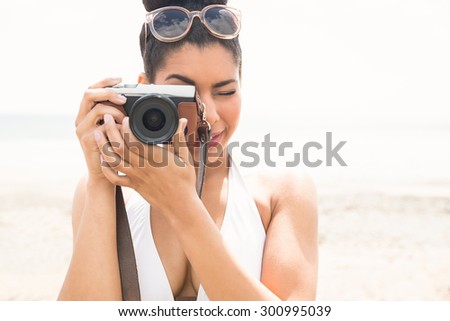 Pretty hipster in bikini taking picture at the beach