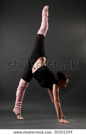 graceful gymnast standing in splits against dark background