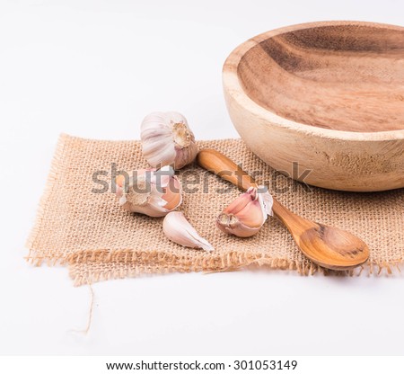 Garlic, onions, wood cups, wooden spoons, put on sackcloth white background.