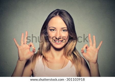 Portrait beautiful happy young woman showing Ok sign with two hands isolated on gray wall background. Positive human emotions face expression body language