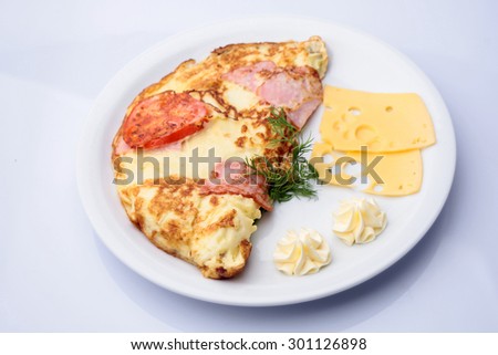 Restaurant food of delicious scrambled folded omelet with bacon tomato cheese dill and sauce on white plate isolated on white, horizontal picture