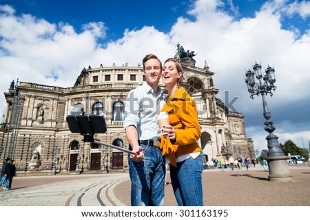 Tourist couple at Semperoper in Dresden taking selfie with phone on stick