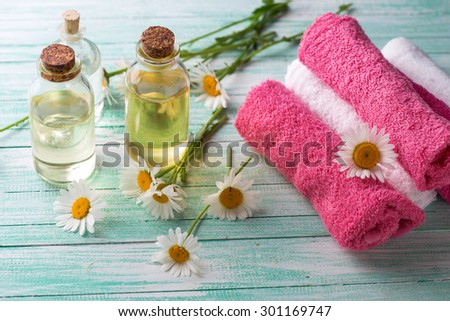 Spa setting. Essential aroma oil with chamomile and towels on  turquoise painted wooden background. Selective focus.