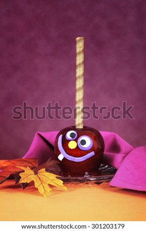 Bright Halloween candy apple with cute funny face in bright orange and pink maroon background. 
