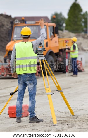 Surveyor engineers working with theodolite on road construction site