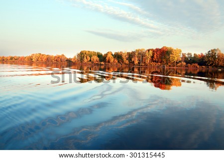 autumn landscape beautiful morning on the river, colorful trees on the beach and clouds on blue sky