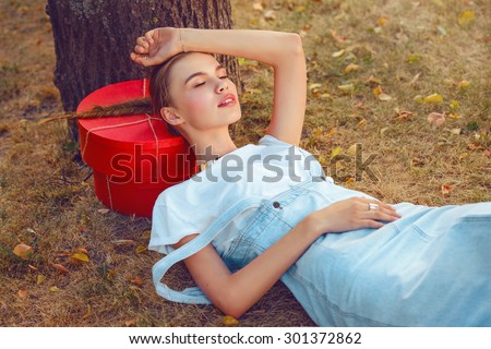 hipster woman in park. jeans city style.seat on a grass in fashionable clothes stockings a sundress