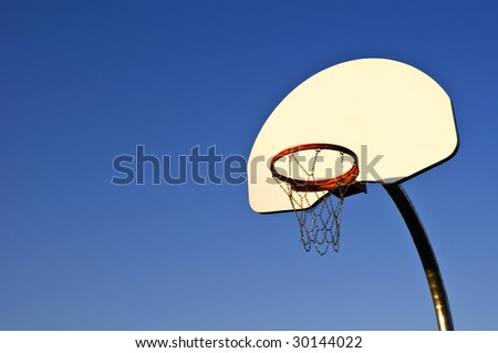 An outdoor basketball hoop with steel chain link net. Deep blue sky and space for copy.