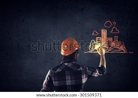 Back view of businessman drawing sketches of construction project on wall