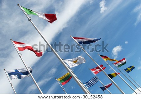 Multi national flags flutter in blue cloudy sky