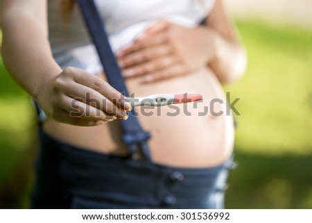 Closeup photo of pregnant woman holding positive pregnancy test