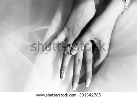 Closeup of female hands with beautiful wedding ring from precious metal on viel fabric of bride dress black and white, horizontal picture