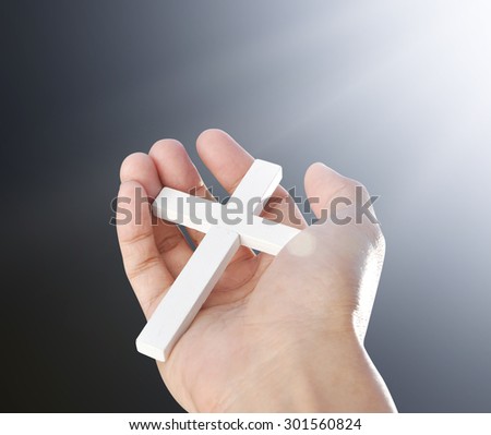 Hand and cross on light beam background , concept design