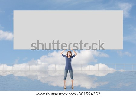 Woman holding blank board standing against the sky.