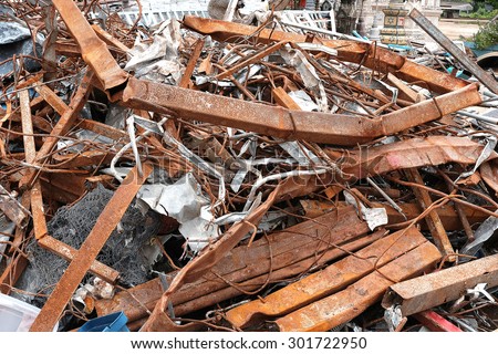 Pile of twisted and rusty scrap steel girders being recycled at a building demolition site.