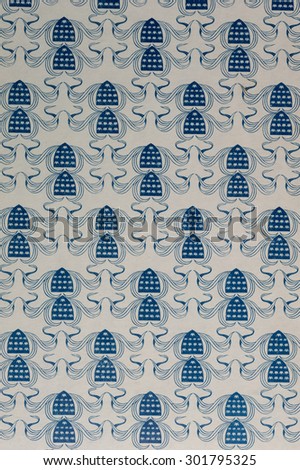 Vintage Hawaiian cloth fragment with a blue floral pattern on a white textured background.