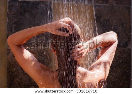 Woman in the shower, back side of young female showering under refreshing water, healthy lifestyle, enjoying time in luxury spa resort  Royalty-Free Stock Photo #301816910