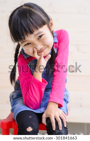 Portrait of a cute little girl on wood background. Smiling after carpenter work.
